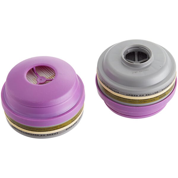 A close up of two Honeywell magenta and olive filters with a white label and grey end.