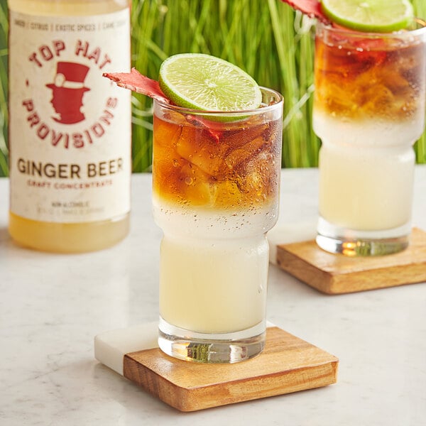 A glass of Top Hat Provisions Spicy Ginger Beer with lime on a coaster.
