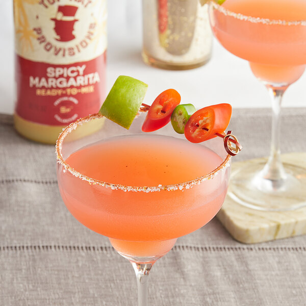 A glass of Top Hat Provisions Spicy Margarita Mix with a tomato garnish on the rim.