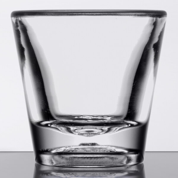 A clear plastic shot glass with a clear bottom on a table.