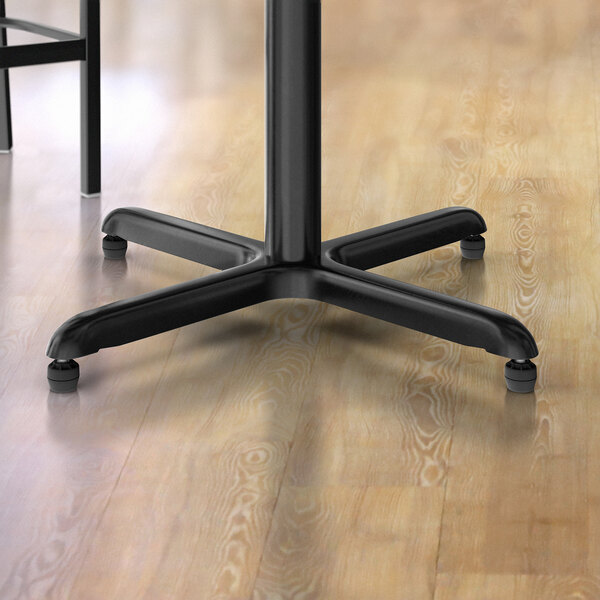 A black table with a Lancaster Table & Seating cross stamped steel table base.