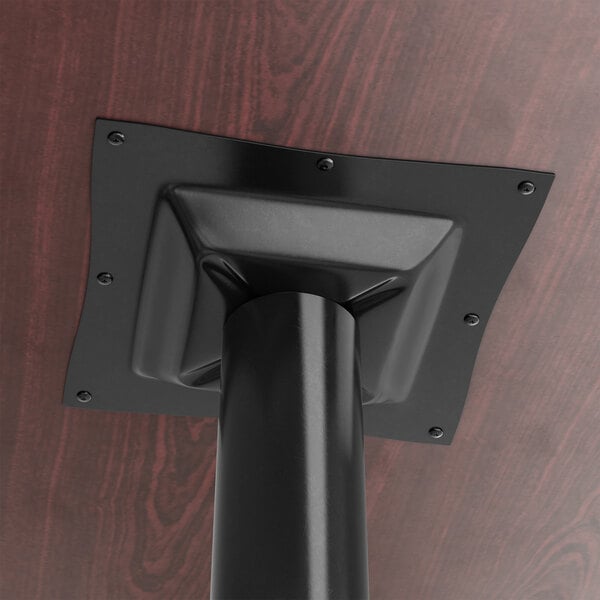 A black metal Lancaster Table & Seating table base spider on a wooden table.