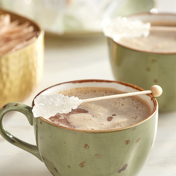 A mug of coffee with a white rock candy stick in it.