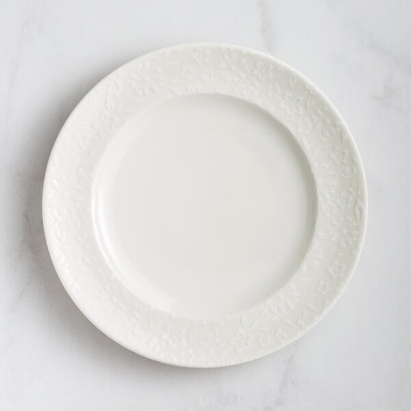 A close-up of a RAK Porcelain ivory flat plate with a floral design.