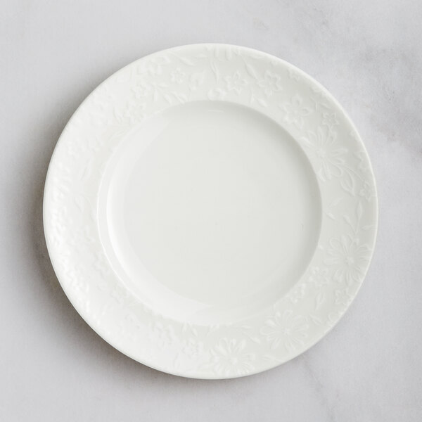 A white RAK Porcelain flat plate with an embossed floral design.