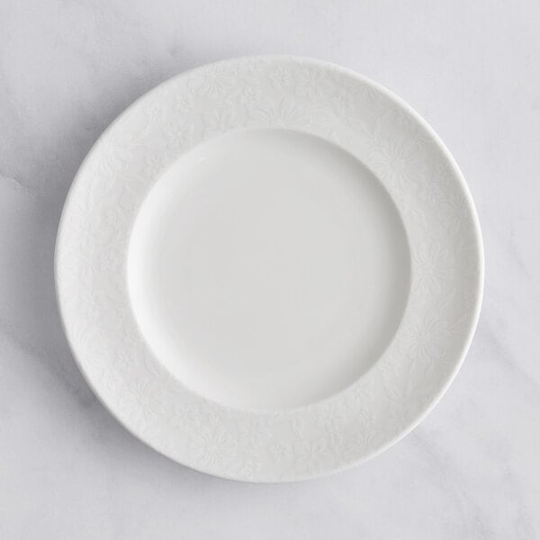 A RAK Porcelain ivory flat plate with an embossed floral pattern on the rim.