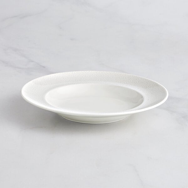 An ivory RAK Porcelain deep plate with an embossed rim.