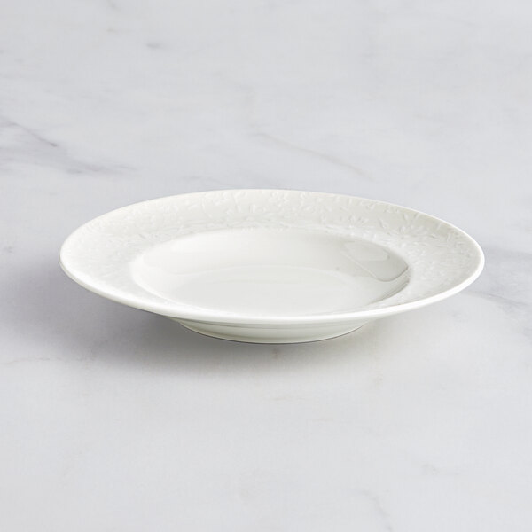 A RAK Porcelain ivory deep plate with an embossed rim on a marble surface.