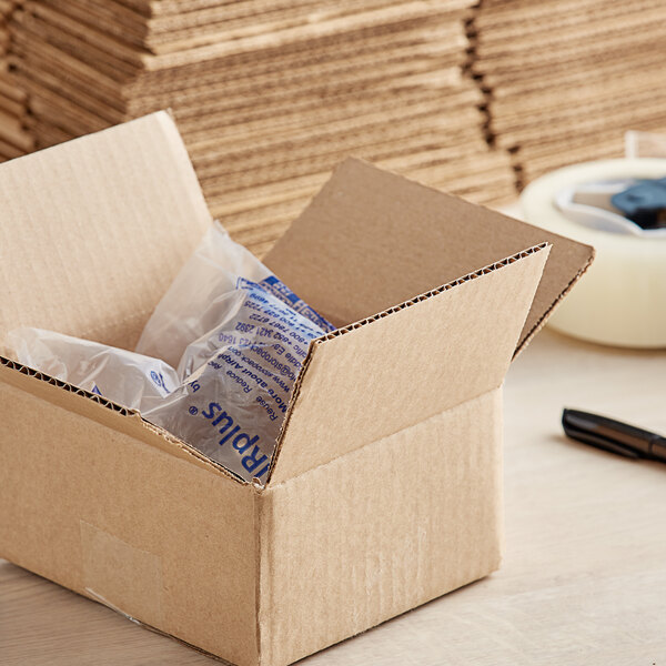 A Lavex Kraft cardboard shipping box with a pen and a clear plastic bag inside.