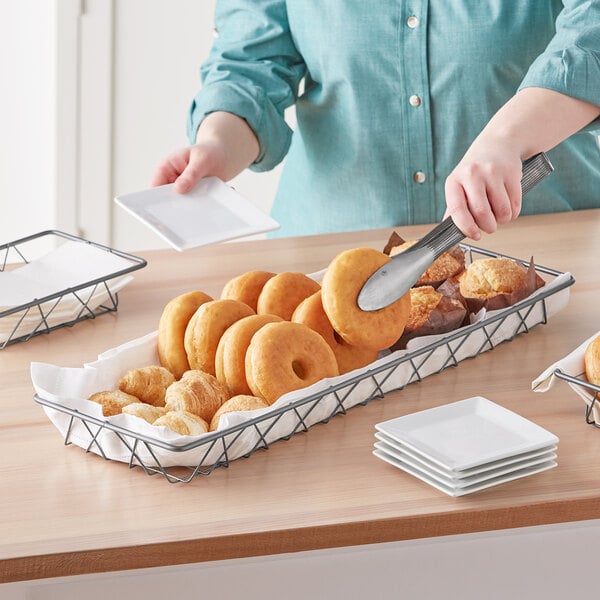 A knife cutting a doughnut in a bakery display basket.