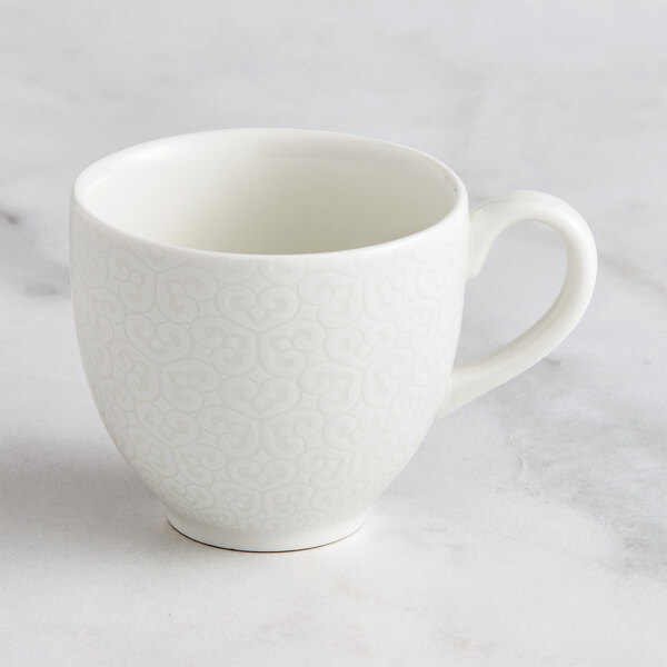 A RAK Porcelain ivory cup with an embossed pattern on a white background.