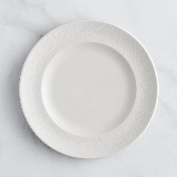 A RAK Porcelain ivory flat plate with an embossed white floral rim.