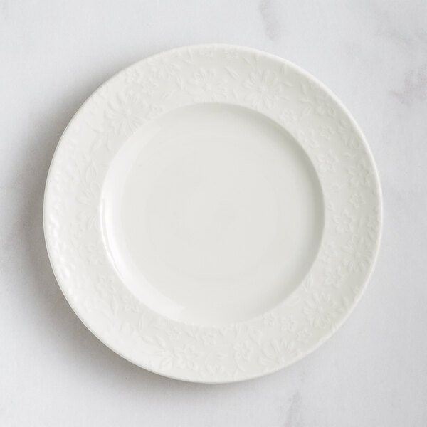 A white RAK Porcelain flat plate with an embossed floral design.