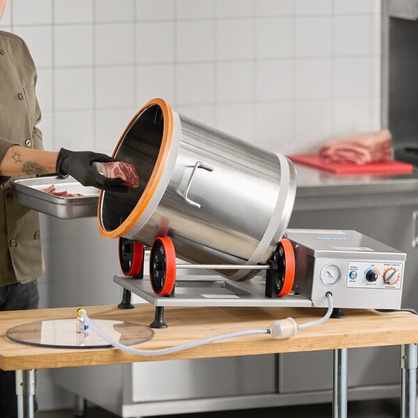 An electric meat and vegetable vacuum marinator with a stainless steel drum and control panel, shown on a countertop in a commercial kitchen.