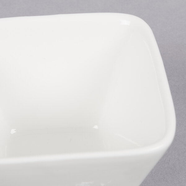 An American Metalcraft white square porcelain sauce cup on a gray surface.