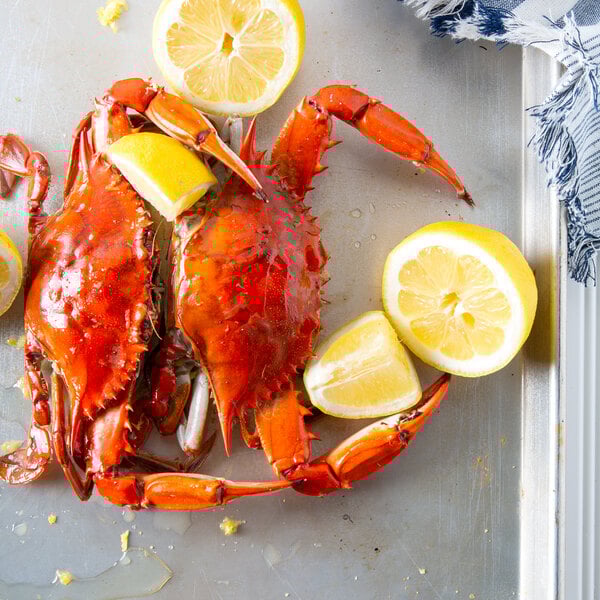A tray with two medium non-seasoned steamed blue crabs and lemon wedges.