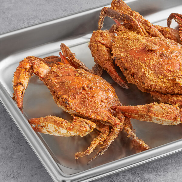 A metal tray of seasoned steamed female blue crabs.