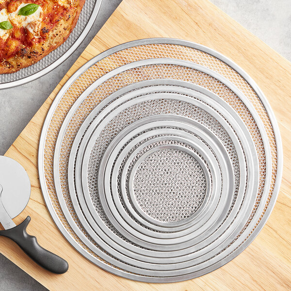 A pizza on a Choice aluminum pizza screen on a cutting board.