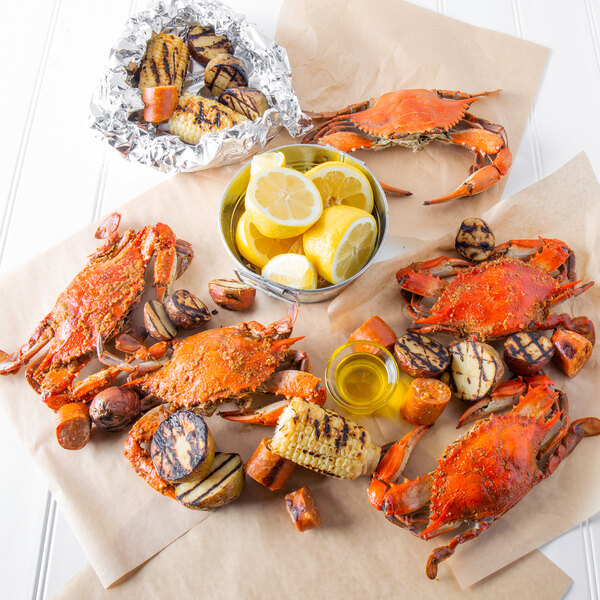 A group of cooked Chesapeake blue crabs with corn and potatoes on a table.