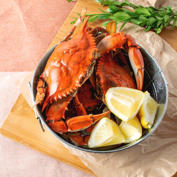 A bowl of Chesapeake blue crabs with lemon wedges.