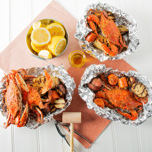Three aluminum foil bowls of Chesapeake Crab Connection small extra seasoned steamed blue crab with lemons.