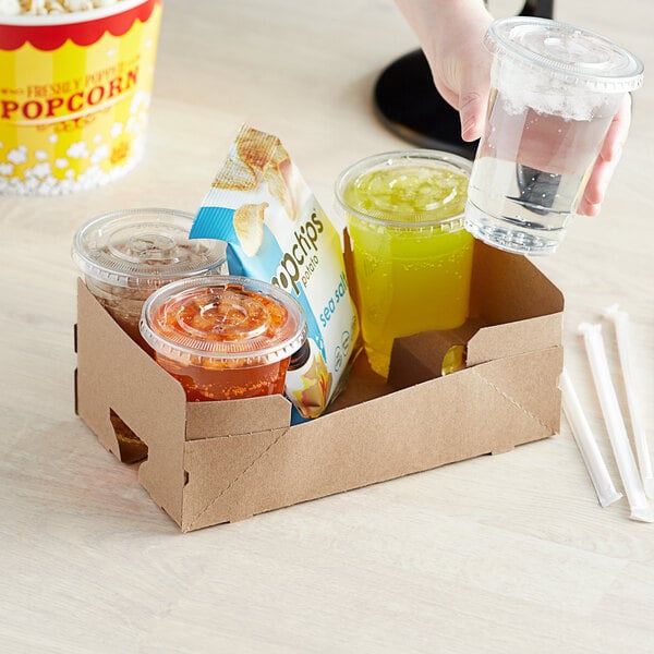 A hand holding a plastic cup of liquid in a Kraft paper carrier.