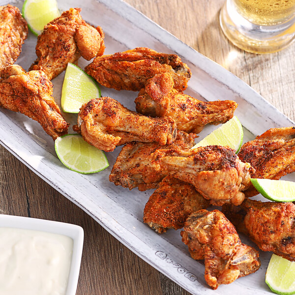 A plate of Regal Maple Chipotle chicken wings with lime wedges.
