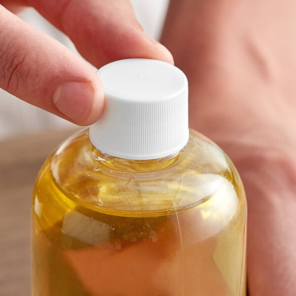 A hand holding a plastic bottle of liquid with a white 20/410 continuous thread lid.