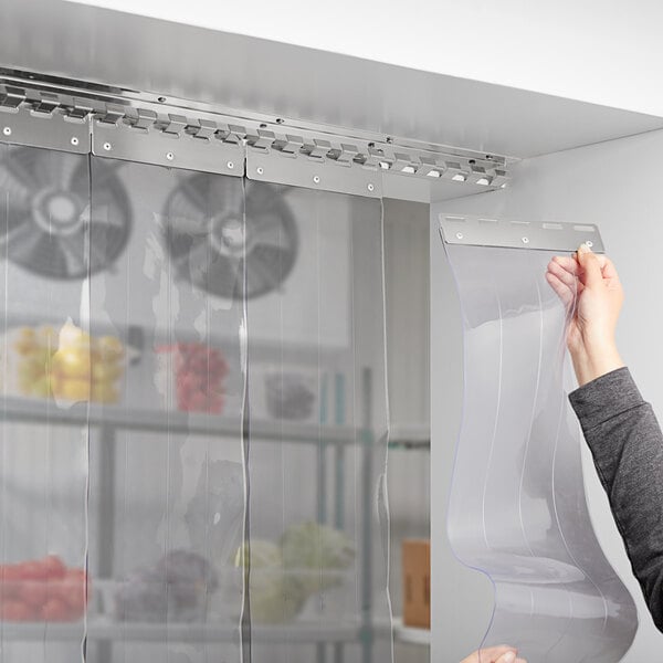 A woman holding a white roll of transparent plastic strip door material.