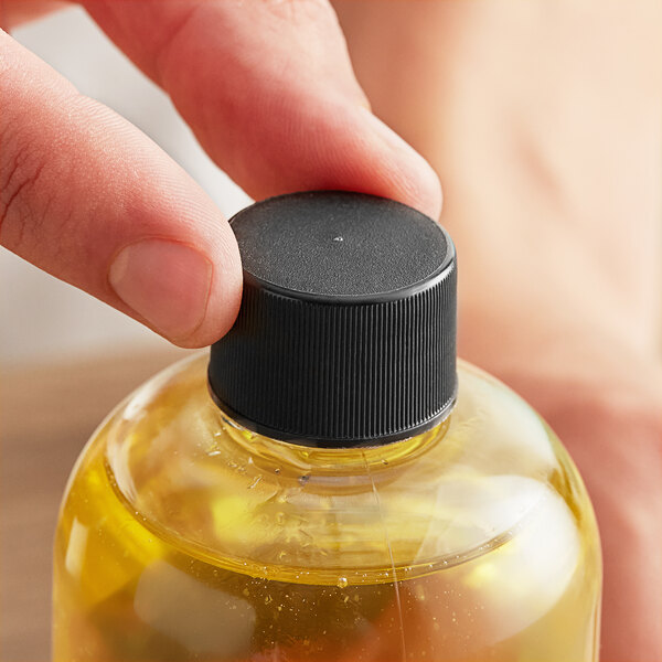 A hand holding a bottle of liquid with a black plastic 24/410 continuous thread lid.