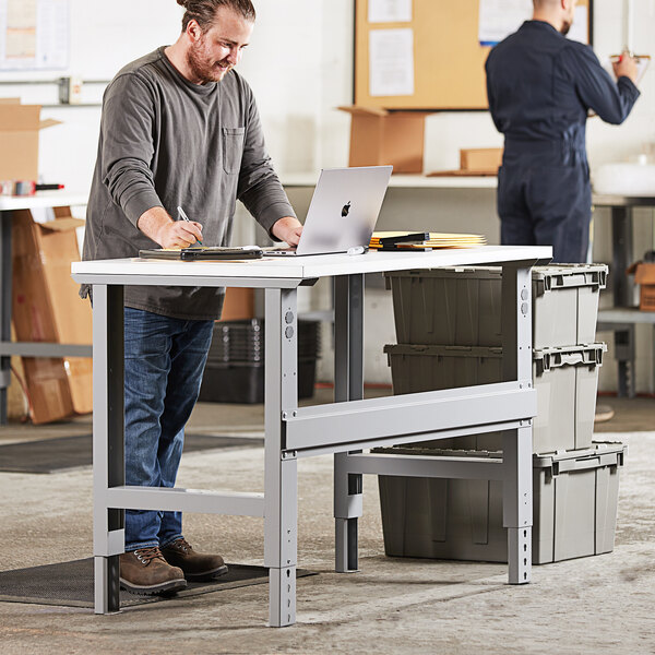 A person standing at a Lavex heavy-duty workbench with a laptop.