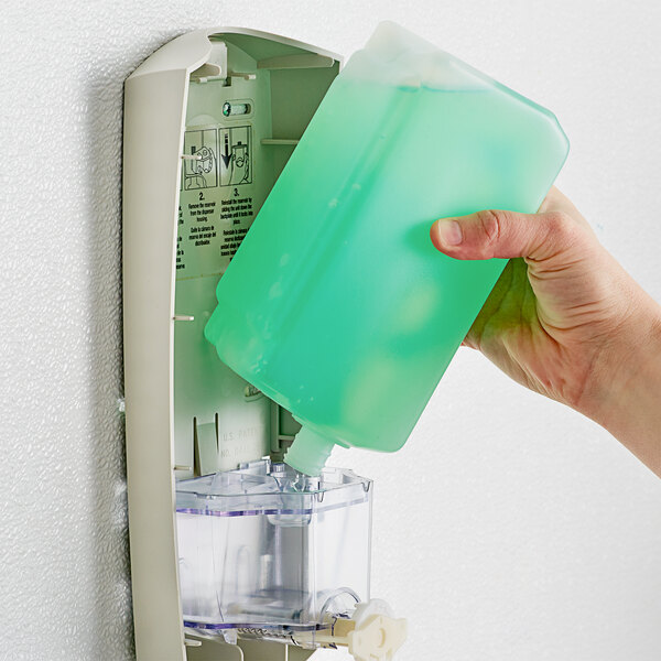 A hand pouring Dial Hypoallergenic Liquid Hand Soap into a green container.