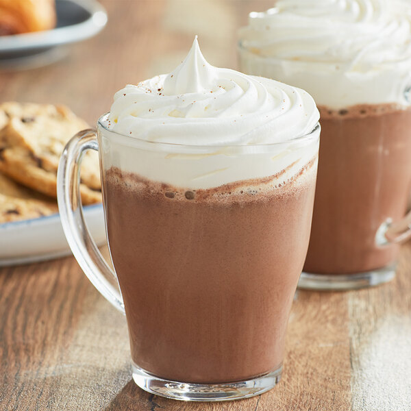A glass mug of Land O Lakes Cocoa Classics Oatmeal Cookie hot chocolate with a cookie on the side.