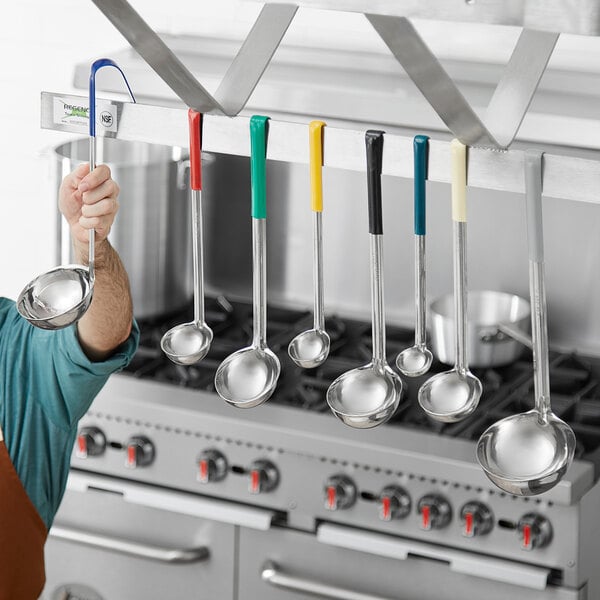 A man holding a Choice stainless steel ladle with a gray handle in a kitchen.