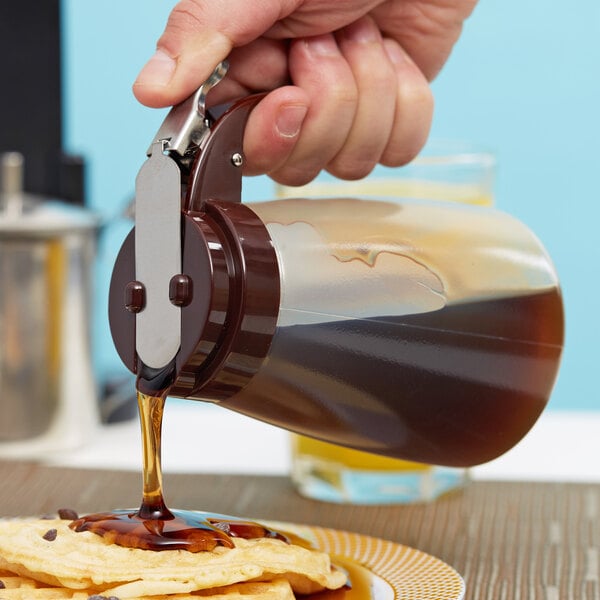 A person pouring Tablecraft syrup onto a plate of food.