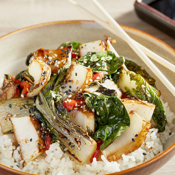 A plate of rice and Bok Choy with chopsticks.