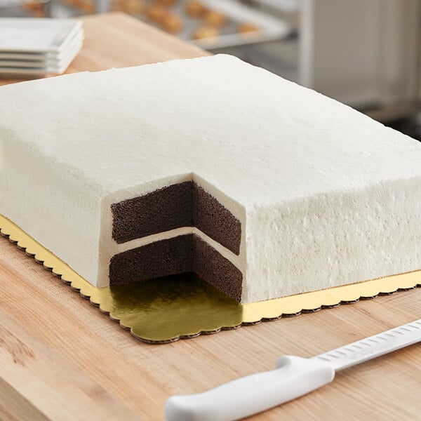 A gold double-wall laminated corrugated half sheet cake board under a cake with white and chocolate layers.