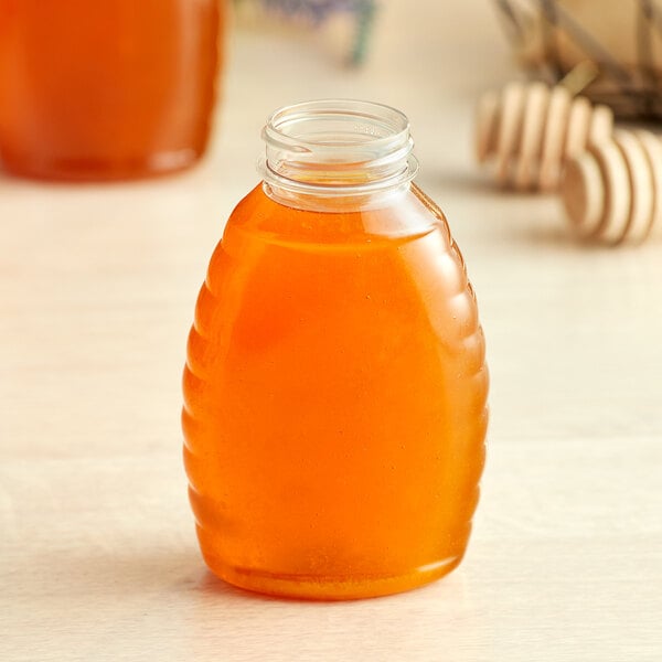 A Classic Queenline PET honey jar with a lid on a table.