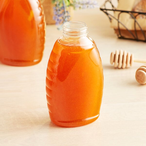 A Classic Queenline PET honey bottle filled with honey on a table.