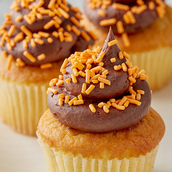 A close up of a cupcake with chocolate frosting and Bake-Stable Orange Sprinkles.