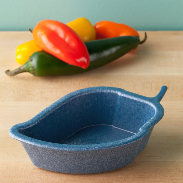 A blue HS Inc. Jalanino salsa server on a wood surface with a red pepper next to it.