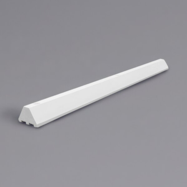 A white rectangular plastic parking block on a gray surface.