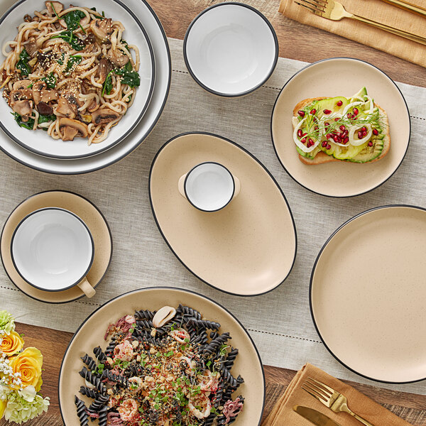 A table with Acopa Harvest Tan Matte stoneware plates and bowls of food.