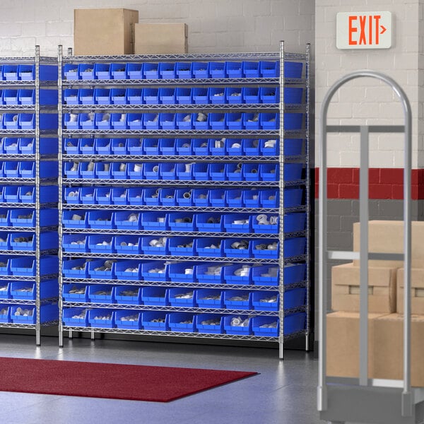 A warehouse with blue bins on shelves and a red rug on the floor.