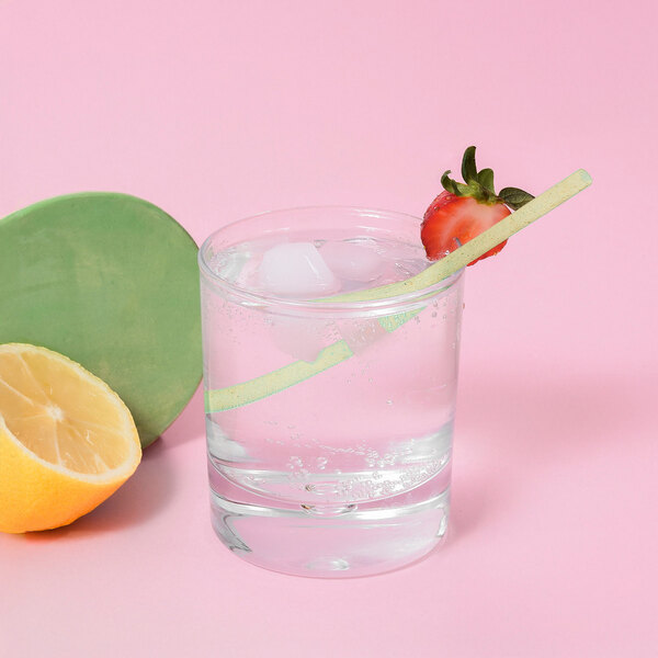 A glass of water with ice and a Greenprint Natural Agave straw with a lemon slice.