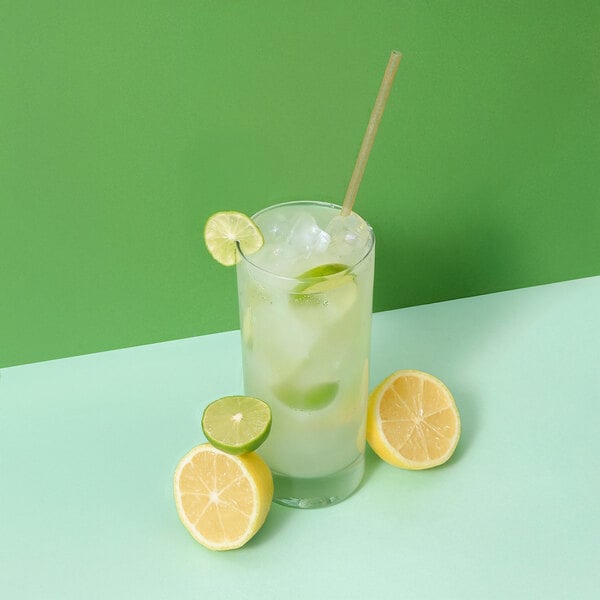 A glass of lemonade with ice, limes, and a Greenprint natural agave straw.