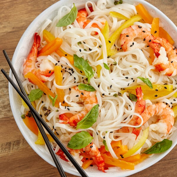 A bowl of Rice Stick Noodles with shrimp and vegetables, and chopsticks.