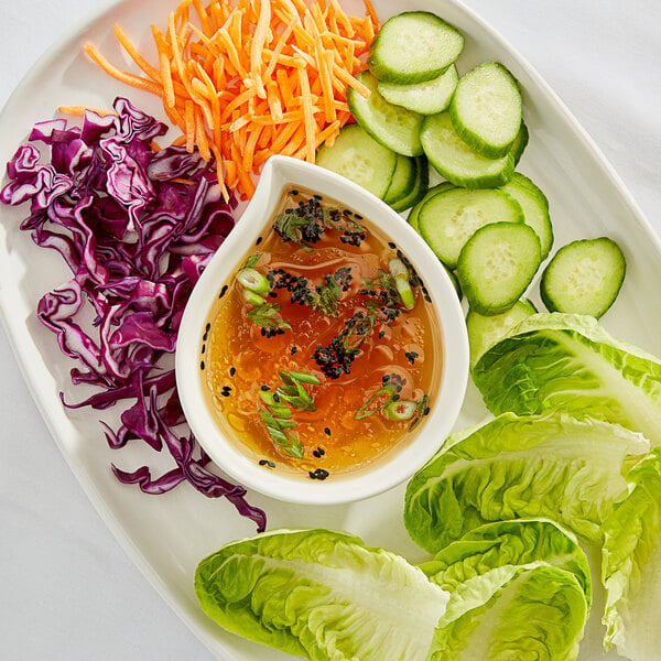 A plate of vegetables with a bowl of fish sauce.