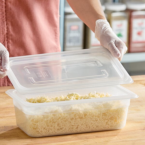 A woman using a Vigor translucent polypropylene lid to seal a plastic container of food.