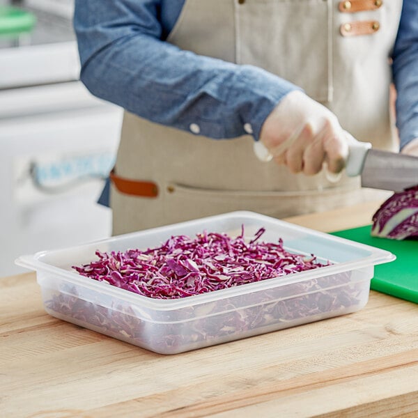 A person cutting red cabbage in a Vigor translucent plastic food pan.